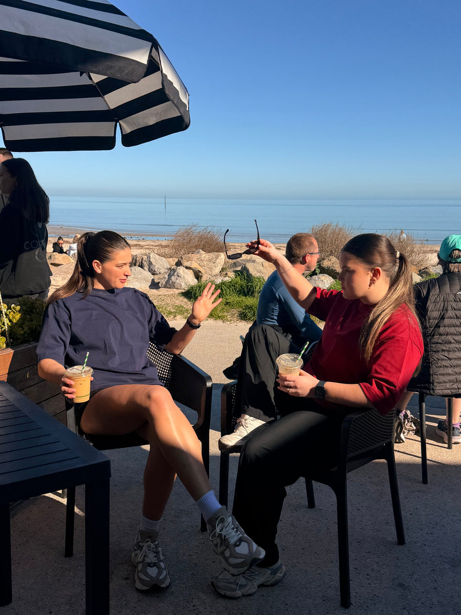 Two friends in Core Form Apparel tees at a beachside café